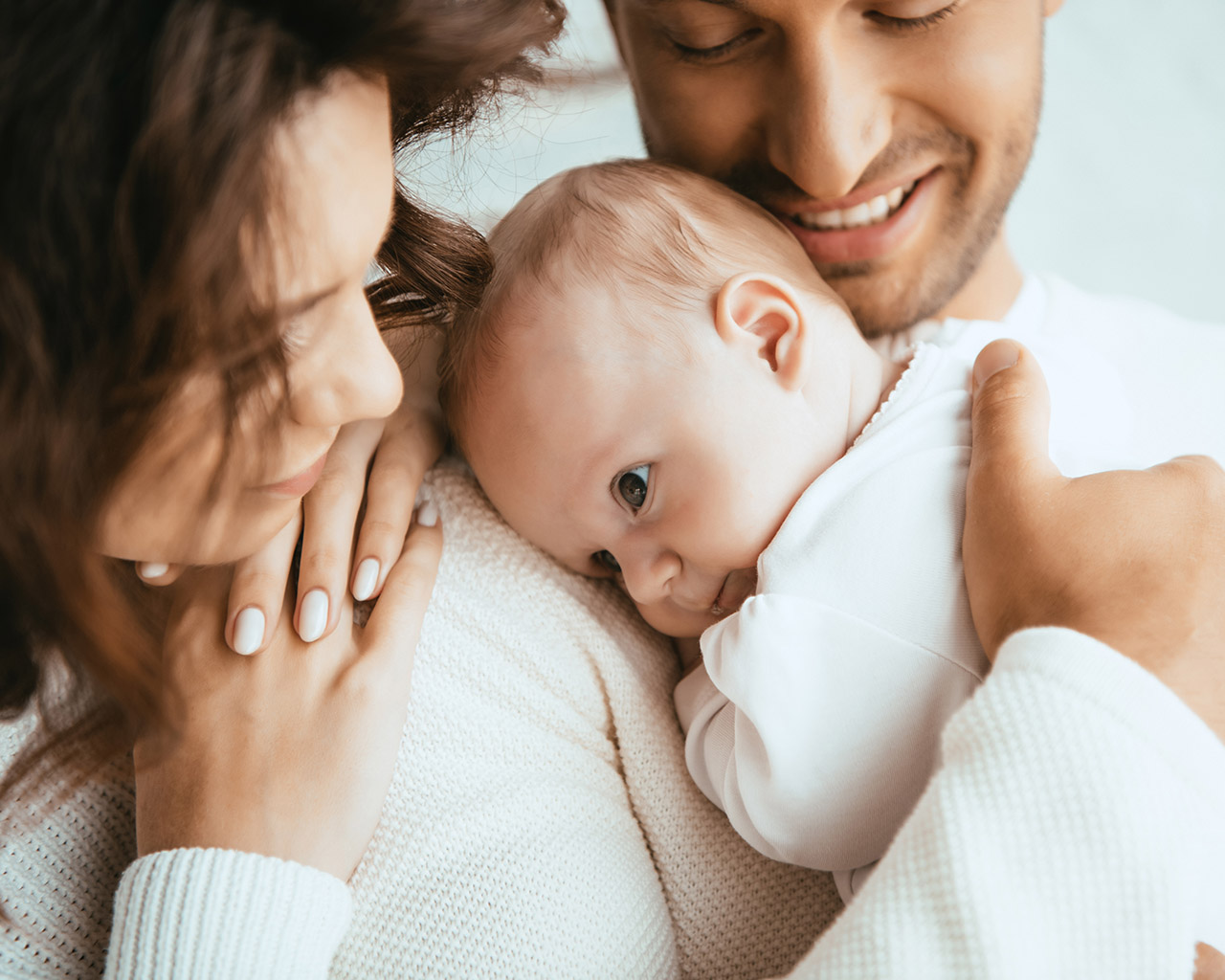 Parents holding a newborn baby during a family healthcare planning moment.