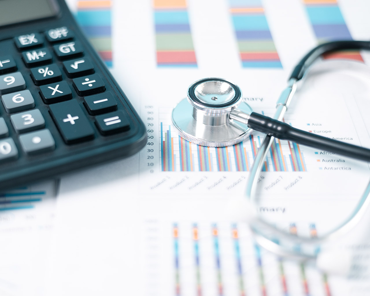 Healthcare costs and insurance planning documents with a calculator and a stethoscope.